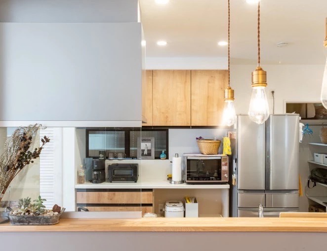 木目のカウンター、ペンダントライト、グレーのレンジフードが特徴的な木目調のキッチン。