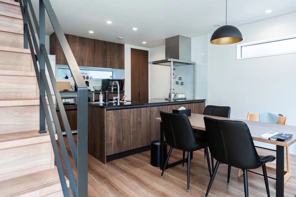 ダークトーンのキッチンとブラックのカウンタートップを持つアイランドキッチン事例。