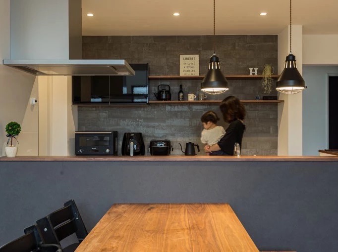 モダンなLDKのインテリアデザイン。ブラックのキッチンと電化製品が並ぶ。