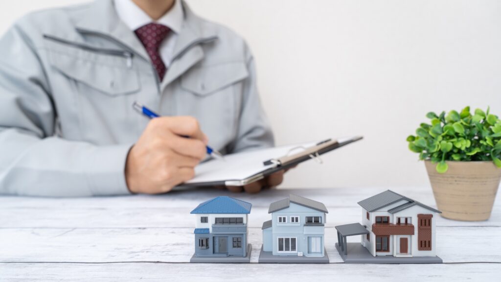 模型の家と作業服の男性