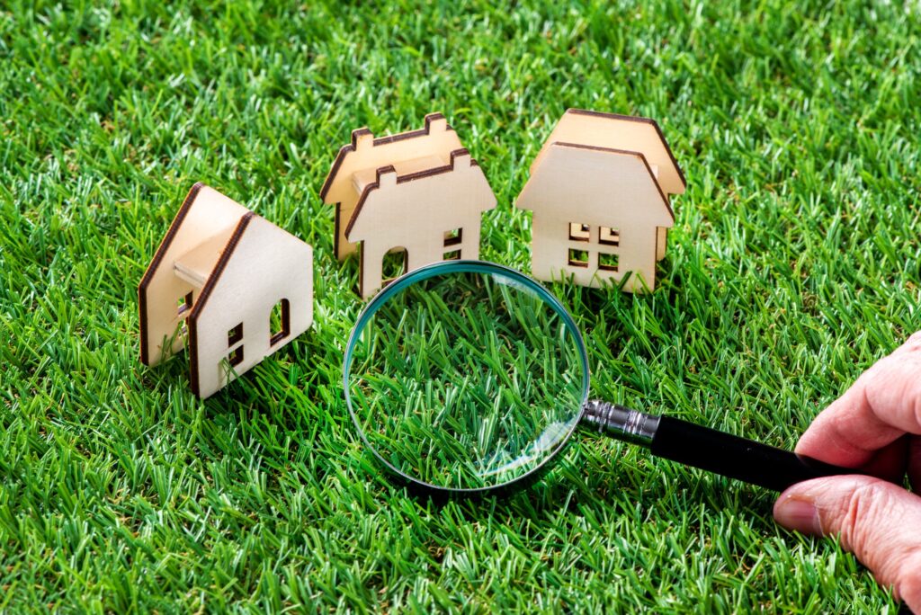 生の上のミニチュアの家と虫眼鏡